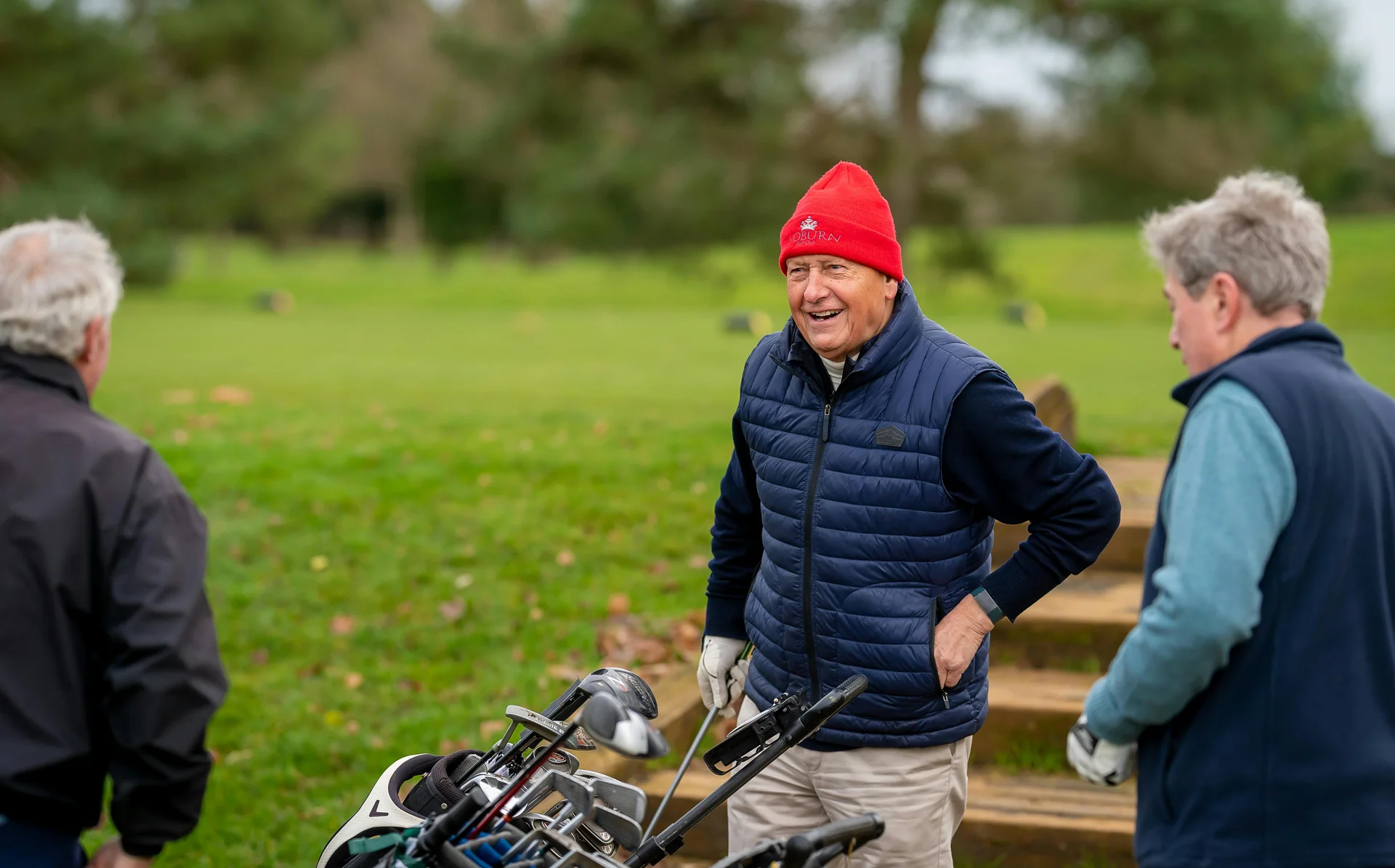 Three senior golfers chatting and laughing together on the course